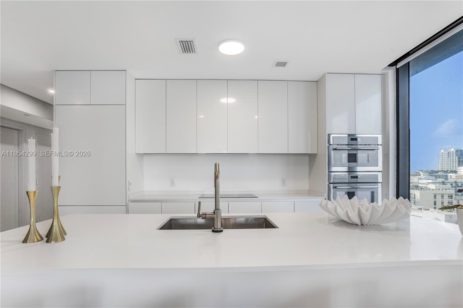 700 Northeast 24th Street, Unit 901 Miami, FL 33137 - Photo 6 of 59 a kitchen with stainless steel appliances a sink a stove and white cabinets