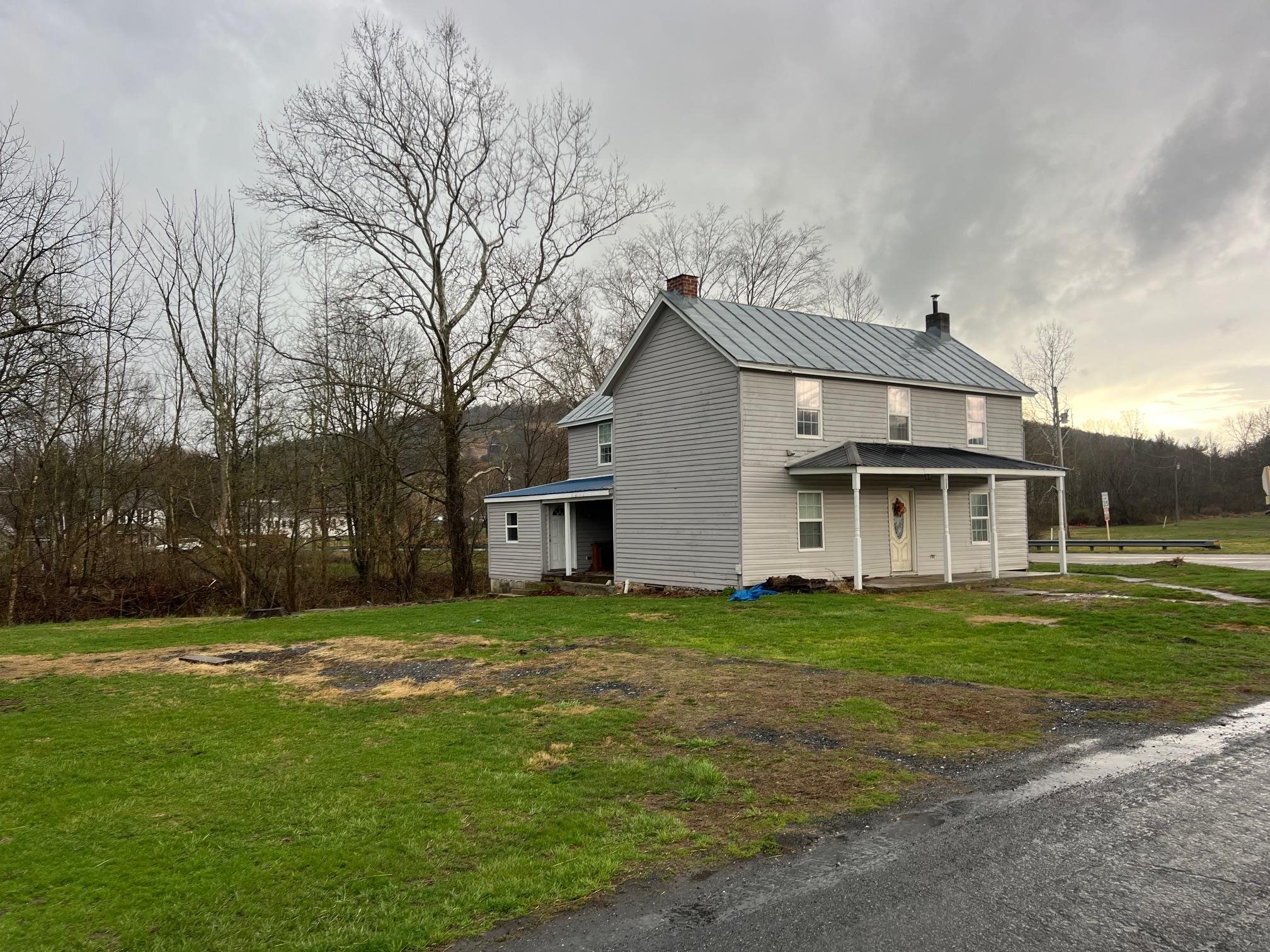 a view of a house with a big yard and large trees