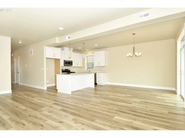 a view of kitchen and empty room with wooden floor