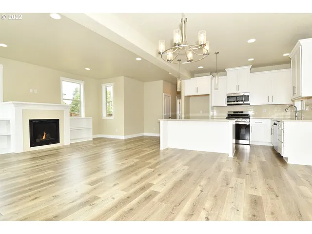 a view of a kitchen with kitchen island wooden floor and stainless steel appliances