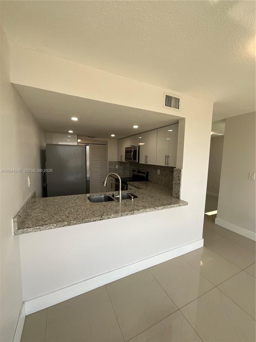 9441 Southwest 4th Street, Unit 214 Miami, FL 33174 - Photo 2 of 22 a bathroom with a granite countertop sink a toilet and a mirror