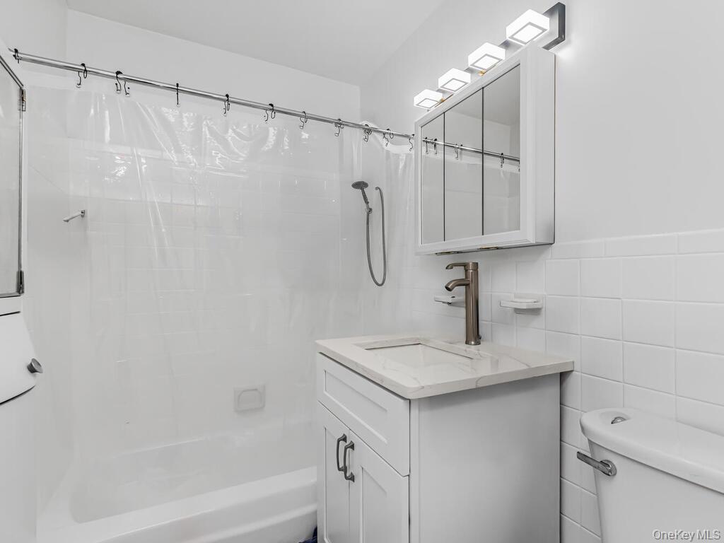 555 Kappock Street, Unit 16K Bronx, NY 10463 - Photo 10 of 16 Bathroom featuring toilet, tile walls, vanity, and shower / bath combination with curtain recently refinished