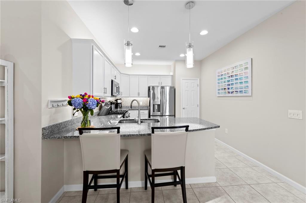 20179 Torch Key Way Estero, FL 33928 - Photo 16 of 41 a dining room filled chandelier and kitchen view