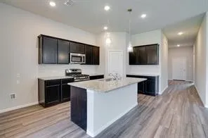 a kitchen with granite countertop a stove top oven a sink dishwasher a refrigerator and a microwave oven with wooden floor