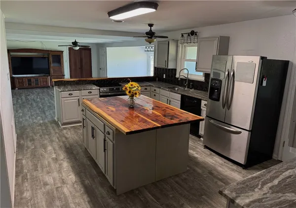 a kitchen with stainless steel appliances granite countertop a refrigerator a stove a sink and a microwave