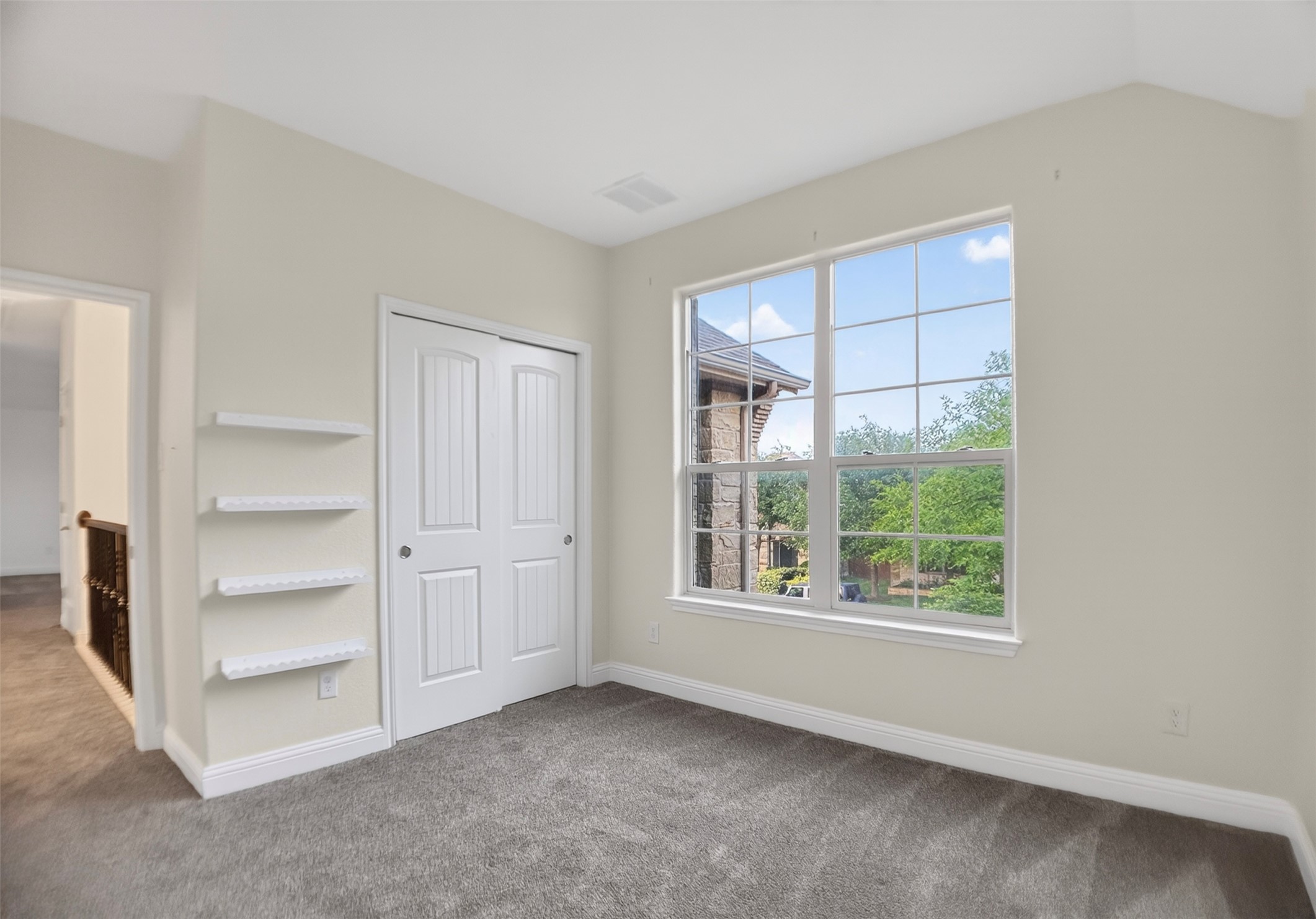 1505 Long Shadow Lane Georgetown, TX 78628 - Photo 25 of 28 Carpeted room featuring a large grid-pattern window, built-in shelving, white bi-fold closet doors, and white baseboards