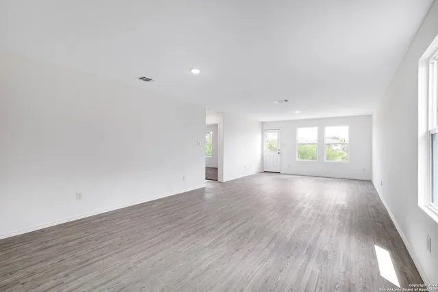 an empty room with wooden floor and windows