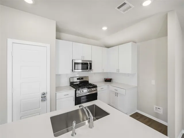 a kitchen with stainless steel appliances a stove a sink and white cabinets