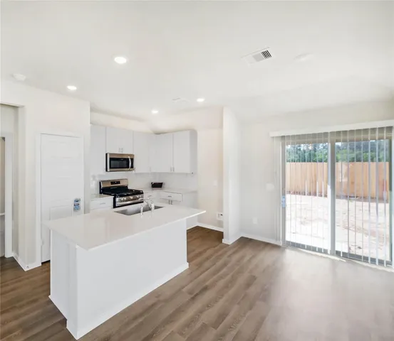 a kitchen with stainless steel appliances a stove top oven a sink a refrigerator a window