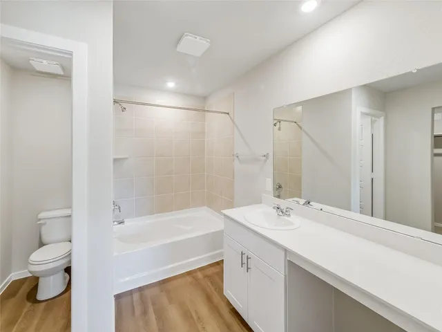 a bathroom with a bathtub shower sink vanity mirror and toilet