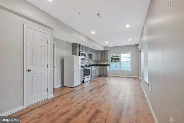 a view of a kitchen with refrigerator and wooden floor