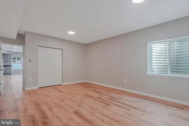 a view of empty room with wooden floor and fan