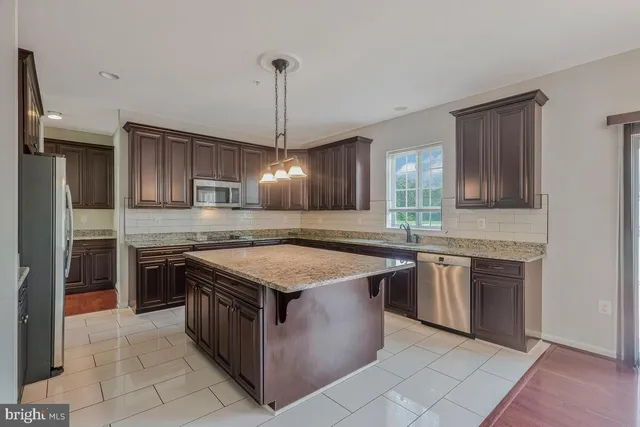 a kitchen with stainless steel appliances granite countertop a stove a sink dishwasher a refrigerator and a oven with wooden floor