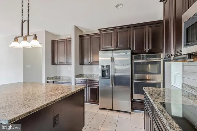 a kitchen with granite countertop a refrigerator and stainless steel appliances
