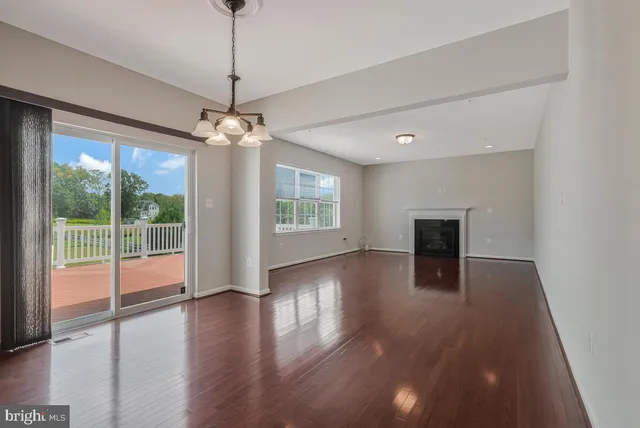a view of a livingroom with wooden floor a ceiling fan and windows