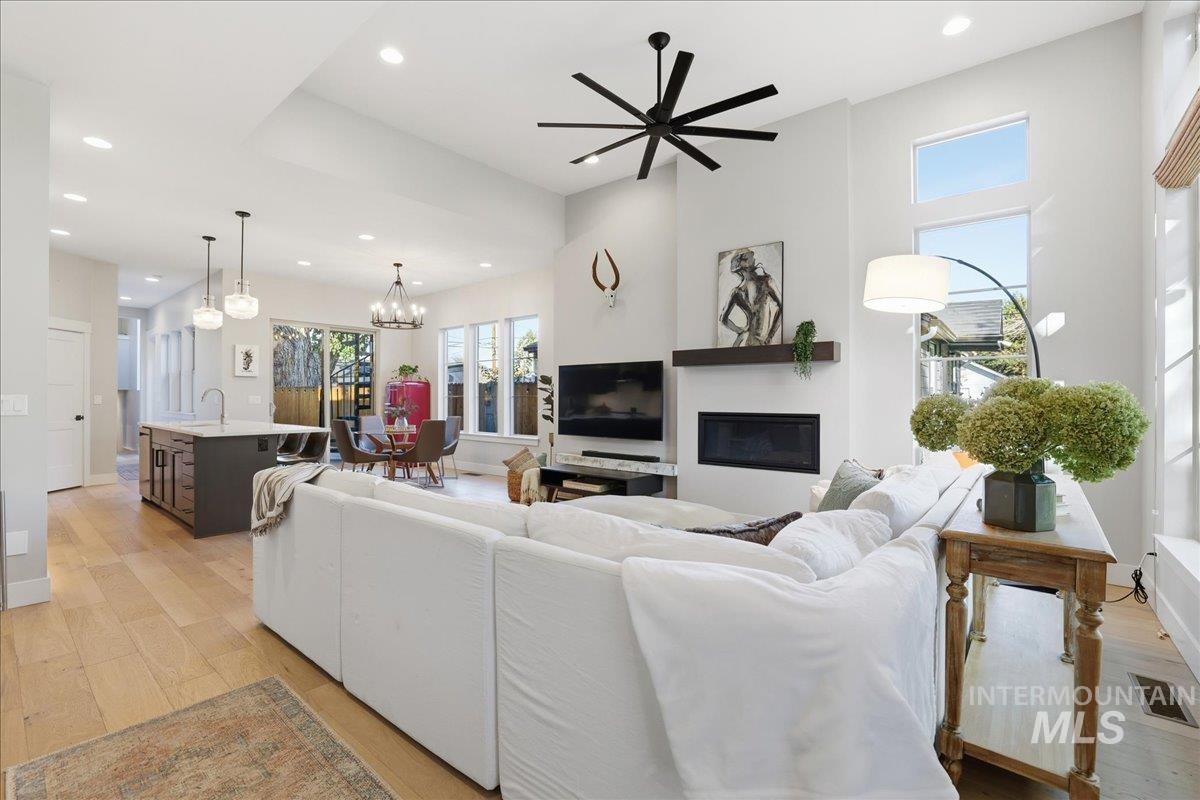 2129 North 34th Street Boise, ID 83703 - Photo 9 of 50 Living room featuring a glass covered fireplace, light wood finished floors, recessed lighting, a ceiling fan, and a chandelier