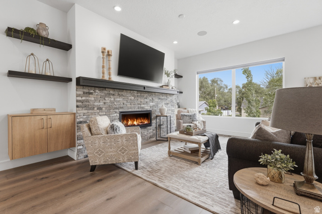 653 East Vandalay Lane Draper, UT 84020 - Photo 11 of 61 Spacious living area featuring light wood-finish flooring, a stone-clad fireplace with a dark mantel, and large windows