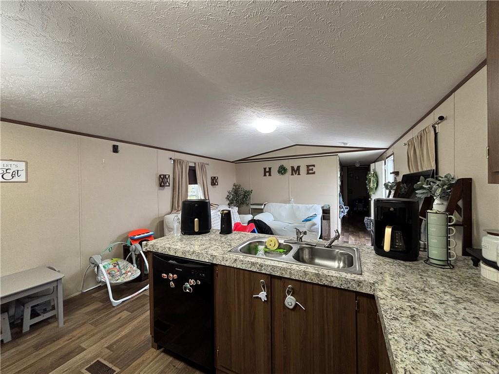 4415 Addison Drive Edinburg, TX 78542 - Photo 5 of 12 Kitchen featuring light countertops, dishwasher, lofted ceiling, a textured ceiling, and dark brown cabinets