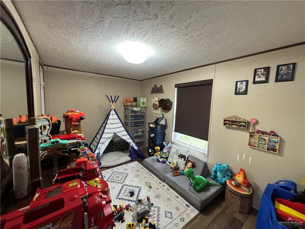 4415 Addison Drive Edinburg, TX 78542 - Photo 9 of 12 Game room featuring a textured ceiling, wood finished floors, and crown molding