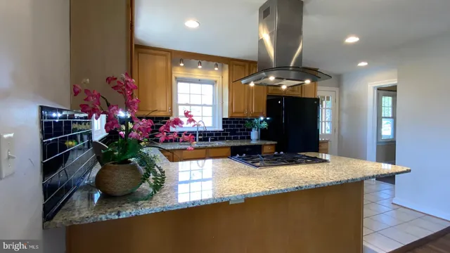 a kitchen with kitchen island granite countertop a sink a counter top space and living room view