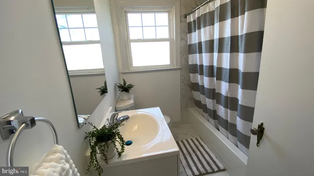 a bathroom with a sink and mirror with bathtub