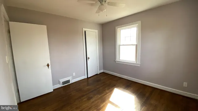 an empty room with wooden floor closet and windows