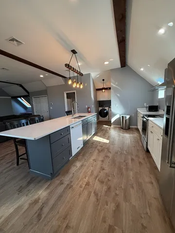 a large kitchen with stainless steel appliances kitchen island a large counter top a sink a stove and a refrigerator