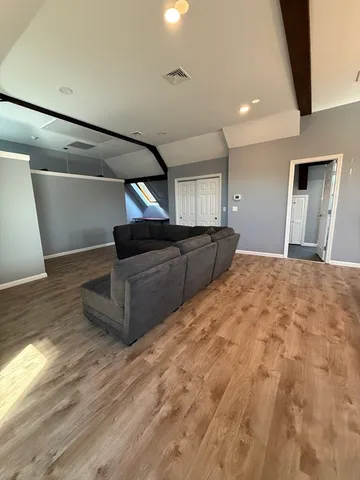 a view of kitchen and empty room with wooden floor
