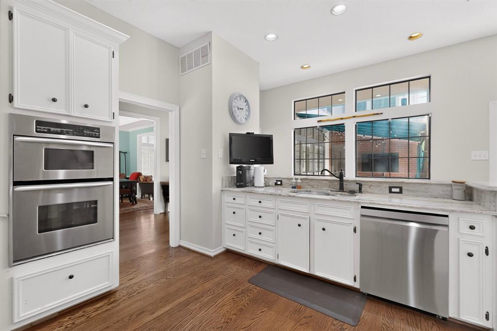 1526 Abrams Road Dallas, TX 75214 - Photo 10 of 38 Hardwood flooring, white cabinetry, stainless steel double oven, undermount sink with black faucet, and transom windows