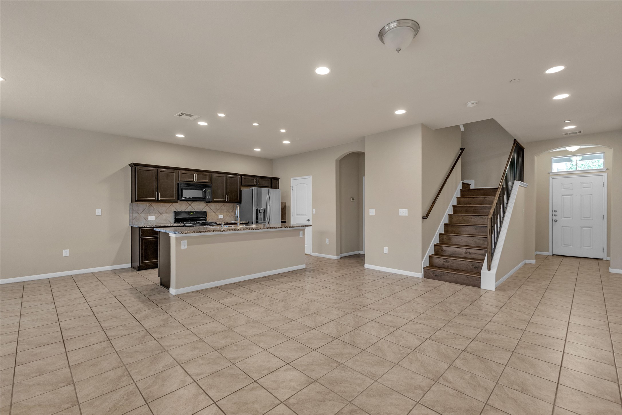 2880 Donnell Drive, Unit 2003 Round Rock, TX 78664 - Photo 6 of 31 Open-concept living space featuring ceramic tile flooring, recessed lighting, a modern kitchen island with seating, dark wood cabinetry, and a full suite of stainless steel appliances