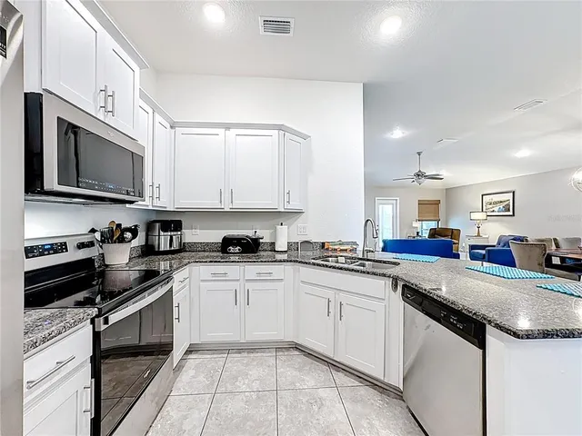 a kitchen with stainless steel appliances granite countertop a sink dishwasher stove and white cabinets