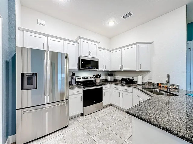 a kitchen with stainless steel appliances granite countertop a refrigerator sink and stove