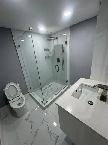 a bathroom with a granite countertop sink a toilet and a shower