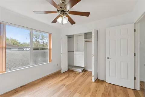 an empty room with wooden floor fan and windows