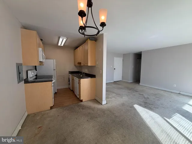 a kitchen with stainless steel appliances granite countertop a sink a stove a refrigerator a washer dryer and a dining table