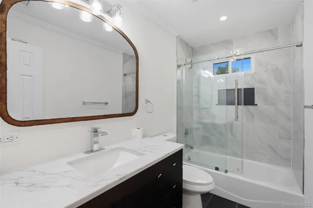 a bathroom with a granite countertop sink a toilet and shower