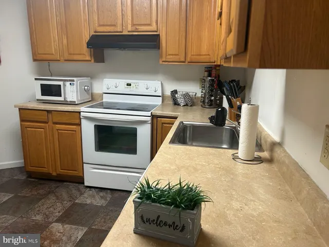 a kitchen with granite countertop a sink stove and cabinets