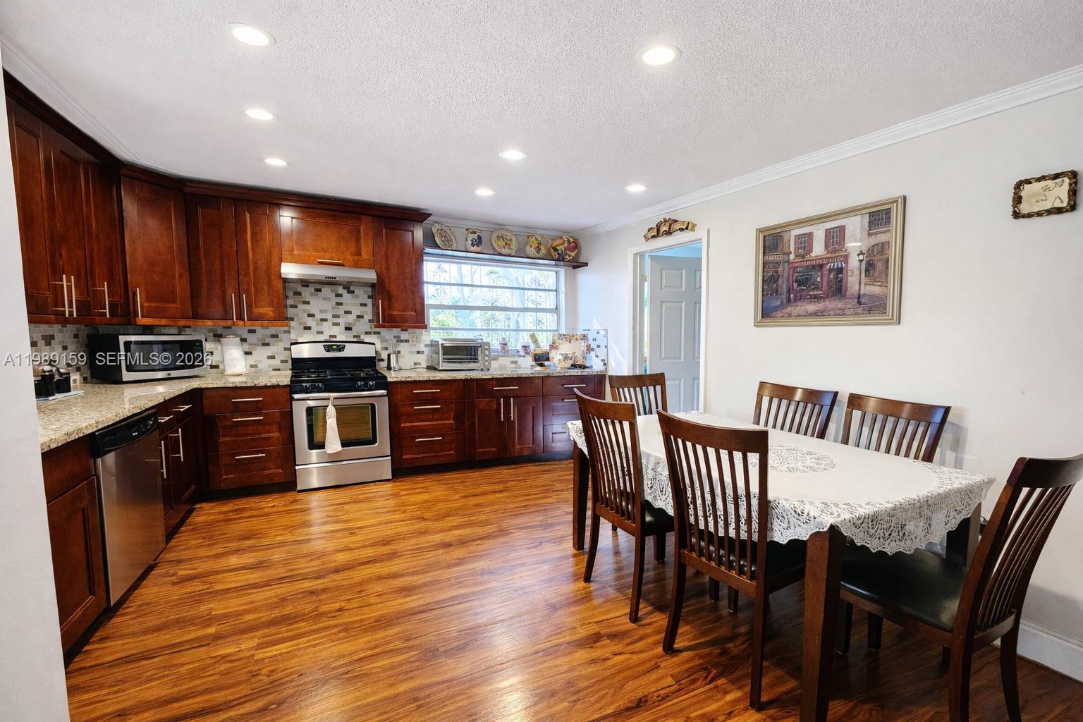 7344 Southwest 135th Court Miami, FL 33183 - Photo 4 of 24 a kitchen with stainless steel appliances granite countertop wooden floor a dining table and chairs