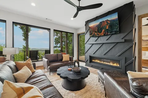 a living room with furniture a large window and wooden floor