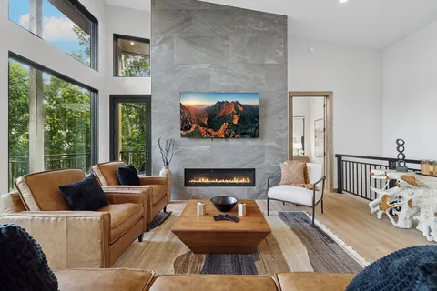 a living room with furniture a fireplace and a floor to ceiling window