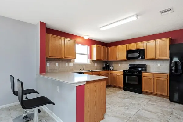 a kitchen with stainless steel appliances granite countertop a stove top oven a sink dishwasher a dining table and chairs with wooden floor