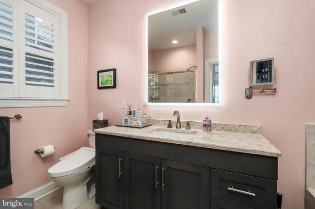 a bathroom with a granite countertop toilet sink and mirror