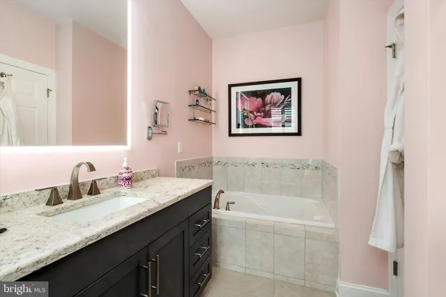 a bathroom with a tub a sink and mirror