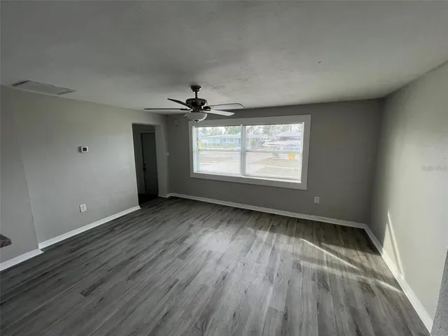 a view of an empty room with a window and wooden floor