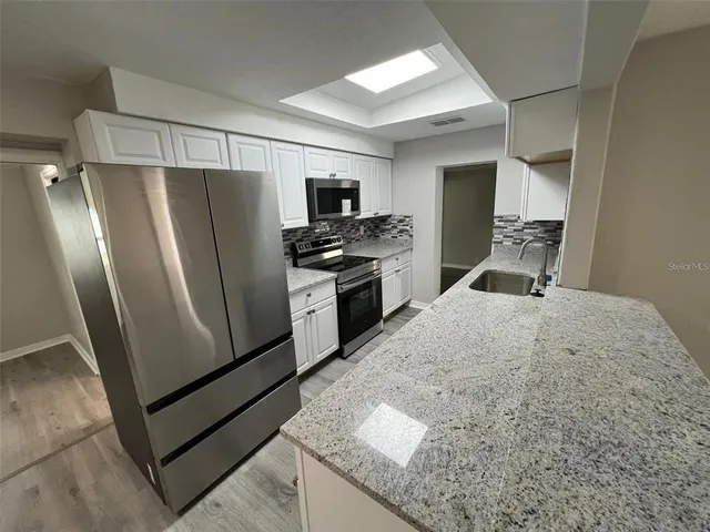 a kitchen with stainless steel appliances granite countertop a refrigerator a stove and a sink