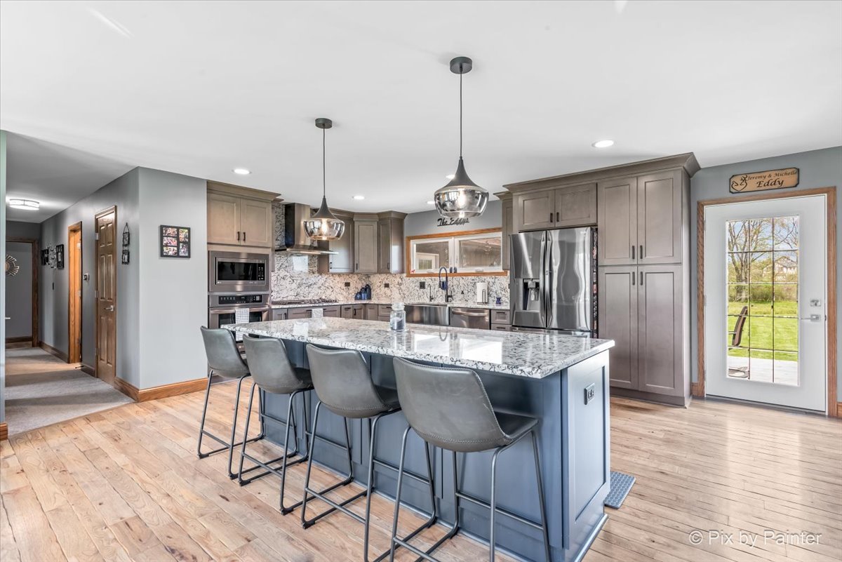 18570 Stevens Road Marengo, IL 60152 - Photo 6 of 45 a kitchen with stainless steel appliances kitchen island granite countertop a table chairs and a refrigerator