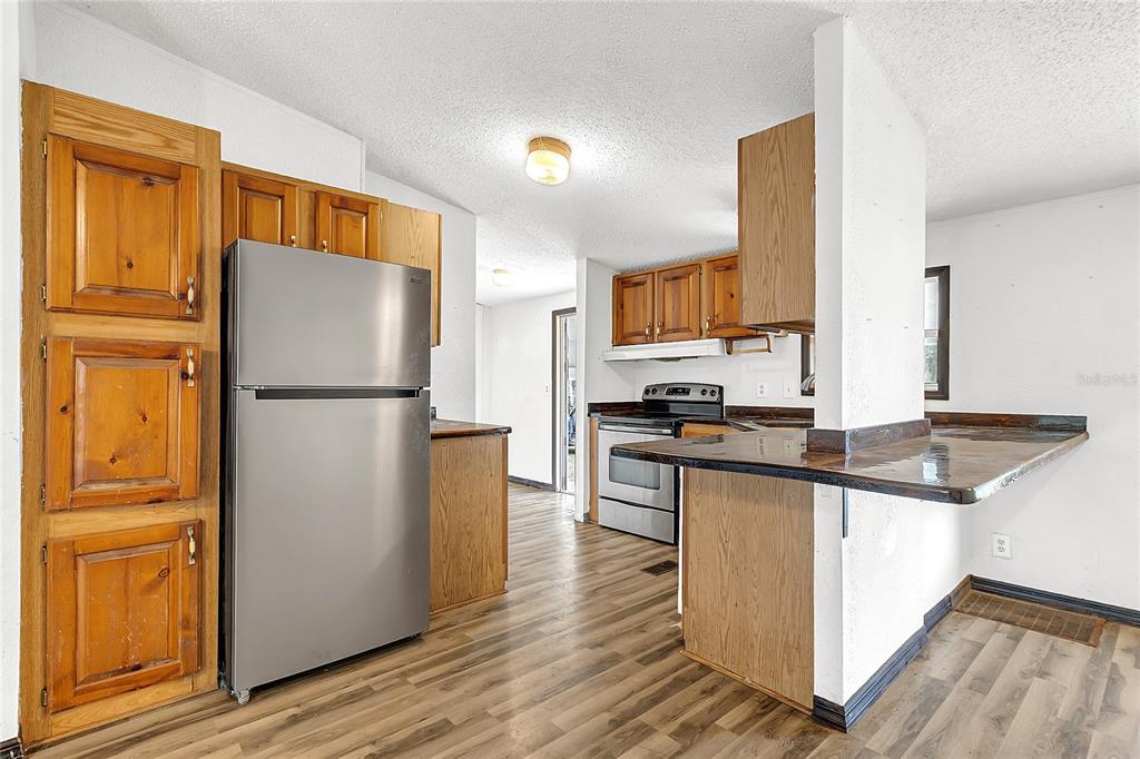 4685 D Street St. Cloud, FL 34772 - Photo 5 of 15 a kitchen with stainless steel appliances granite countertop a refrigerator a stove and a sink with wooden floor