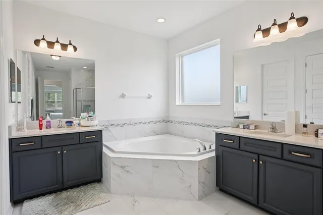 a bathroom with a double vanity sink mirror and bathtub