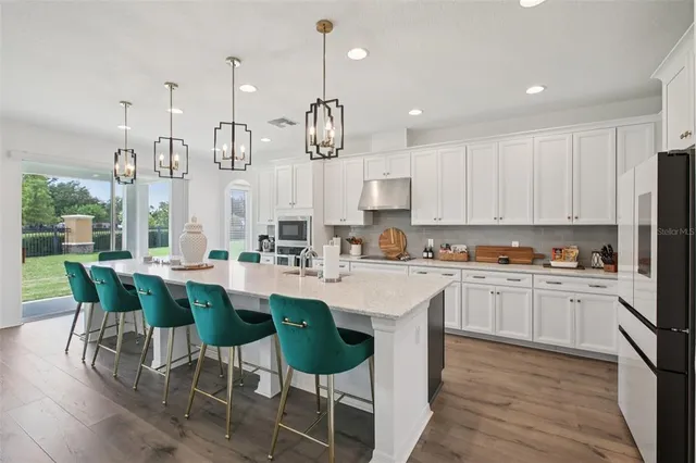 a kitchen with cabinets a sink a stove and chairs in it
