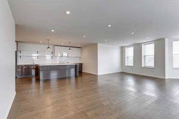 a large white kitchen with kitchen island a sink a stove and a window